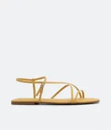 Sandalia plana de mujer color amarillo mostaza, con tiras finas que cruzan sobre el empeine y una tira con hebilla ajustable alrededor del tobillo.