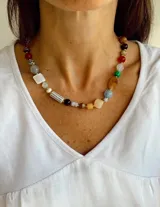Collar de cuentas multicolor con piedras de diversas formas, tamaños y texturas, intercaladas con pequeñas esferas doradas.