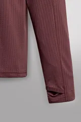 Sudadera técnica color vino tinto, de manga larga, con cuello subido y cierre frontal de cremallera. Presenta un bolsillo frontal con cierre de cremallera oculta en costura y detalle de logo estampado. El tejido tiene estructura waffle en el interior.