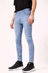 Pantalón de jean en tono celeste claro, con corte skinny fit, bolsillos laterales y traseros, y cierre frontal con botón.