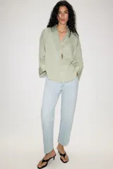 Camisa oversize color verde menta, con cuello camisero, cierre frontal de botones, bolsillo de parche en el pecho y mangas anchas por debajo del codo.