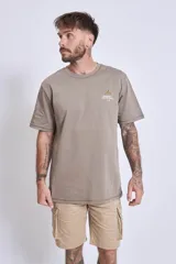 Remera blanca de algodón, corte holgado, con cuello redondo y un pequeño logo bordado en azul claro en el pecho.