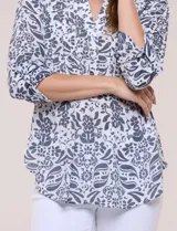 Blusa Zac & Rachel de gasa estampada con diseño floral en tonos violeta y marrón. Cuenta con cuello en V, escote con botones frontales, detalles plisados en el frente y mangas largas con presilla para regular su largo.