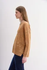 Sweater de moldería relajada, color camel, con escote redondo y manga larga. Tejido jacquard con diseño floral en lurex a tono que simula transparencias.