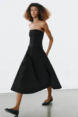 Falda midi de tiro alto en color negro, con diseño en línea evasé y cierre de cremallera oculta en la costura.