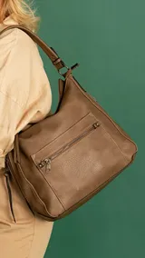 Cartera tipo hobo de tamaño mediano, confeccionada en símil cuero color marrón. Presenta un bolsillo frontal con cierre metálico, correa de hombro fija y diseño con costuras reforzadas.