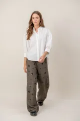 Pantalón de lana de corte recto y holgado, color marrón con textura jaspeada y apliques decorativos oscuros distribuidos por toda la prenda.