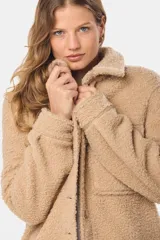 Campera tipo camisa confeccionada en tejido de sherpa, con cuello clásico, cierre frontal de botones y bolsillos delanteros con solapa.