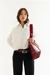 Camisa de corte oversize y estilo casual, confeccionada en algodón negro con costuras a contratono en color blanco. Presenta cuello camisero, cierre frontal parcial, mangas largas y un bordado distintivo en el puño.