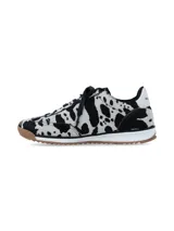 Championes de diseño urbano con estampado animal print tipo vaca en tonos blanco y negro, con franjas laterales blancas, cordones negros, entresuela blanca y suela de goma con relieve.