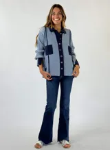 Saco de punto color azul claro con detalles en azul marino. Tiene cuello polo, cierre frontal con botones, mangas largas y dos bolsillos delanteros.