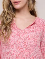 Blusa holgada de gasa liviana con estampado floral en tonos rosados y blancos. Presenta escote en V con muesca central y mangas largas abullonadas con inserción de puntilla y puños elastizados.