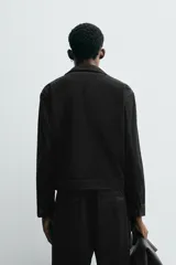 Sobrecamisa de corte cropped confeccionada en terciopelo con elasticidad. Presenta cuello solapa, cierre frontal con cremallera metálica, bolsillos de vivo en la cadera y mangas largas con puños abotonados.