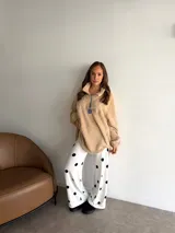 Buzo de corderito color marrón, con cuello alto y cierre frontal parcial. Presenta un diseño holgado con mangas largas y un parche decorativo en el frente.