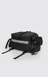 Bolso contenedor negro diseñado para bicicleta, confeccionado en textil de alta resistencia. Cuenta con dos compartimentos independientes con cierres metálicos, dos bolsillos laterales, cinta reflectiva frontal y correas reforzadas para montaje.
