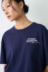 Remera de algodón gris melange con corte oversize, manga corta y estampa localizada en el frente con motivos deportivos en tonos verde y rosado.