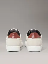 Zapatillas de corte bajo Calvin Klein Jeans en color beige, confeccionadas en una combinación de ante y piel nobuck. Presentan un diseño minimalista con suela cupsole blanca, detalle de trabilla trasera en color marrón y forro interior en contraste negro. Incluye el logo de la marca grabado en el lateral y en la mediasuela.