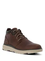 Botín Hush Puppies modelo William, confeccionado en cuero marrón con cordones bicolor. Presenta un diseño de caña media con cuello acolchado y suela de EVA en tono beige con base dentada.