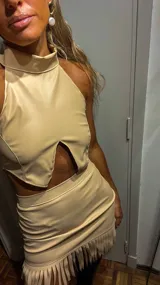 Top polera beige de cuero sintético con cuello alto, corte halter y abertura en el abdomen.