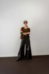 Pantalón de cuero ovino italiano de tiro medio y corte ancho. Presenta costuras diagonales en las piernas que aportan volumen y vuelo, con pretina y pasacintos confeccionados en gamuza al tono.