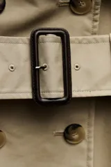 Trench confeccionado en mezcla de algodón color beige. Cuello solapa de muescas y manga larga ajustable con trabillas y botón. Bolsillos en delantero. Cinturón en mismo tejido ajustable con hebilla. Detalle de trabillas en hombros. Cierre frontal cruzado con botones.