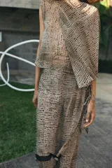 Falda pantalón de tiro bajo con estampado de puntos negros sobre fondo beige. Presenta un diseño de superposición con cierre lateral mediante lazadas y cremallera oculta, finalizando en bordes con detalle de franja negra.