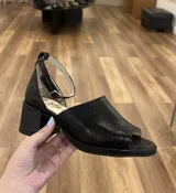 Sandalias de cuero negro con textura tipo piel de serpiente, con tira en el tobillo y taco bajo cuadrado.