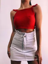 Crop top negro con textura brillante, breteles anchos con volados y espalda descubierta que se ata con lazos.