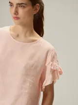Blusa de lino color rosado, de corte recto y holgado, con cuello redondo y mangas cortas adornadas con volados.