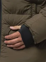 Campera puffer color verde militar, con diseño capitoneado, cuello alto y capucha integrada. Cuenta con cierre frontal, bolsillos laterales con cierre y puños con ojal para el pulgar.