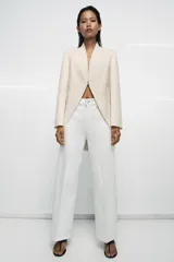 Jeans blancos de tiro alto con diseño wide leg, detalle de nervio delantero y pespuntes marcados a contraste. Presenta cierre frontal con cremallera y botón, y cinco bolsillos.