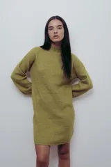Vestido corto de punto color fucsia, con cuello alto y mangas largas amplias. Diseño holgado y cómodo.