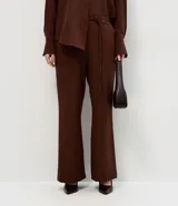 Pantalón sastre de corte wide leg en tejido crepé color marrón chocolate. Presenta una silueta recta y fluida, con cintura elástica y lazo ajustable para un calce cómodo.