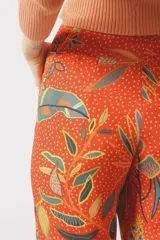 Pantalón de viscosa color naranja con estampado de hojas y lunares.