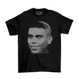 Remera negra de algodón con estampado frontal en escala de grises que representa el rostro del futbolista Ronaldo Nazario con su icónico corte de pelo del mundial 2002 y su firma.