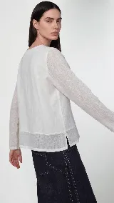 Remera de manga larga confeccionada en una combinación de lino y algodón. Presenta escote en V, diseño con cortes frontales y detalle de logo bordado. Posee un calce cómodo con aberturas laterales en el ruedo.
