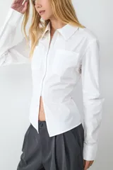 Camisa de popelina negra de manga larga, con cuello clásico y cierre frontal de cremallera con abertura en el bajo.