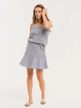 Falda corta acampanada de lino a rayas verticales azules y blancas, con volado godet y cierre trasero invisible.