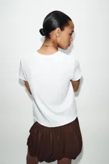 Remera blanca de algodón, de corte regular fit, cuello redondo y manga corta con acabados sin costuras.