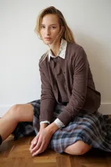 Cardigan azul de punto fino, con cuello redondo y cierre frontal de botones negros.