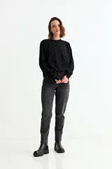 Sweater de punto negro con estampado de pequeños corazones dorados, cuello redondo y mangas largas.