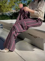 Pantalon de corte cargo con diseño a rayas verticales en tonos marrón, blanco y bordó. Presenta bolsillos laterales tipo cargo, tiro alto y pernera ancha.