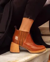 Botinetas de cuero con diseño combinado en texturas. Presenta una puntera con textura tipo reptil, paneles laterales de gamuza y talón en cuero charolado. Cuenta con un taco cuadrado de madera y suela de plataforma.