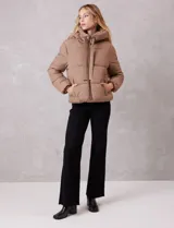 Campera puffer de corte recto y acabado mate, con diseño de bloques horizontales acolchados. Presenta capucha integrada con cordones de ajuste, cierre frontal metálico y bolsillos laterales invisibles. Incluye puños elásticos internos para mayor protección contra el frío.