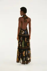 Vestido largo negro con cuello halter y diseño sin mangas, confeccionado en tejido liviano con estampado multicolor inspirado en elementos barrocos y tropicales.