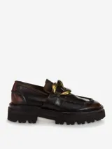 Mocasines de cuero con acabado desgastado, detalle de cadena metálica dorada en el empeine y suela track robusta.
