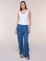 Pantalón palazzo de rayón color azul con estampado paisley blanco, corte amplio, tiro medio-alto con pretina elastizada y aberturas laterales en el puño regulables con lazos.