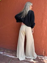 Pantalón palazzo de seda color beige, de corte sastrero y tiro alto.