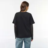 Camiseta negra de algodón con diseño 2 en 1, que combina un cuerpo de remera de manga corta con mangas largas integradas de encaje floral.