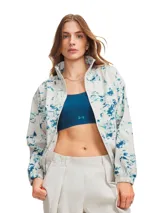 Campera deportiva Under Armour con cierre frontal completo, cuello alto y diseño estampado en tonos azul y blanco. Cuenta con bolsillos laterales con cierre, hombros caídos y puños elásticos.